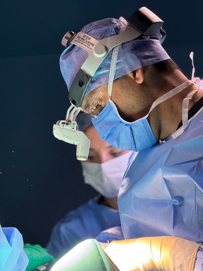 Services-03 Surgeons in blue scrubs focus intensely during a medical procedure in a hospital operating room.